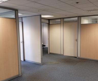 Existing office interior with dated partition layout, suspended ceiling, and carpet tile before a proposed reconfiguration